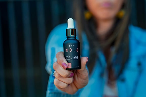 closeup of CBD bottle being held by a woman in evening setting