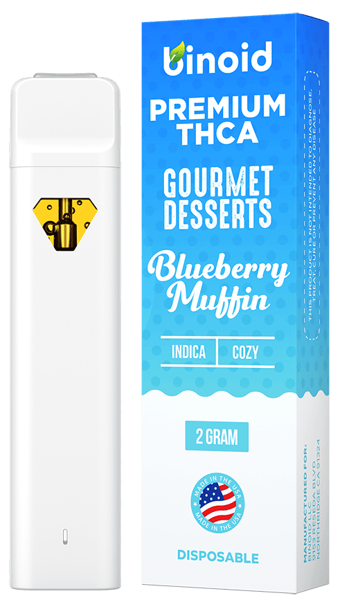 White disposable vape pen with yellow hexagonal logo next to blue and white Binoid Premium THCA Gourmet Desserts Blueberry Muffin product box, 2 gram indica strain